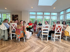 Group of people sitting around a table in a bright room with large windows.