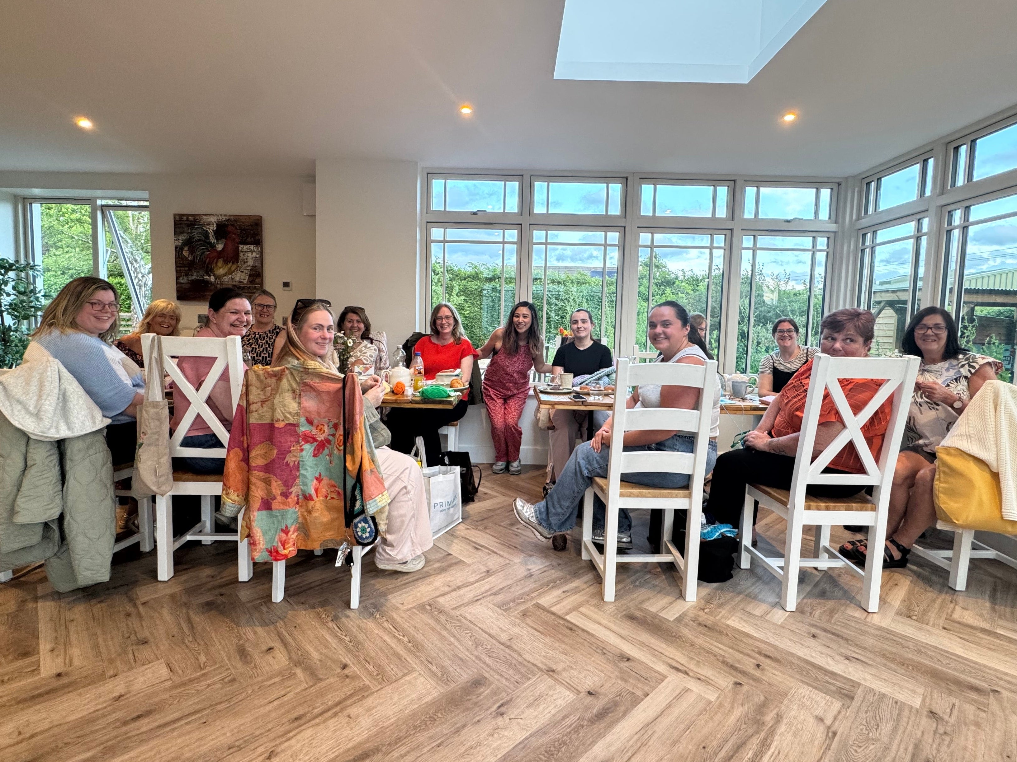Group of people sitting around a table in a bright room with large windows.